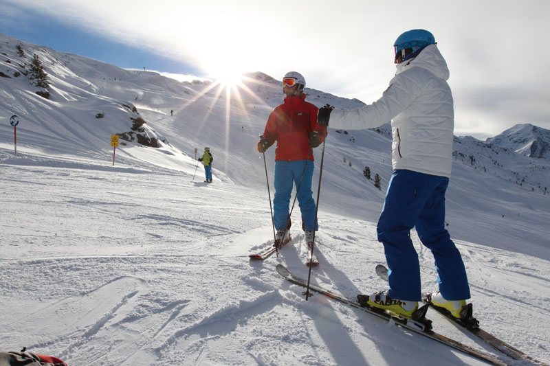 2 Skifahrer mit Sonne im Hintergrund